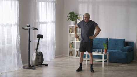 elderly-man-is-doing-physical-exercises-in-light-living-room-at-weekend-morning-healthy-lifestyle-for-middle-aged-and-old-people
